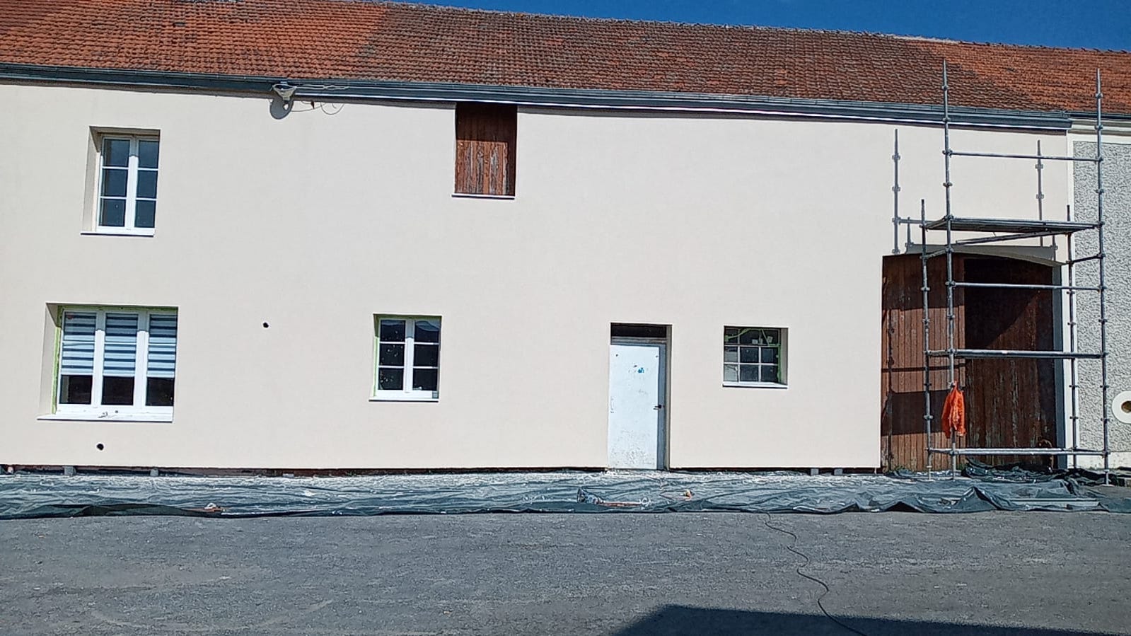 Longère avec façade enduite claire, échafaudage encore en place