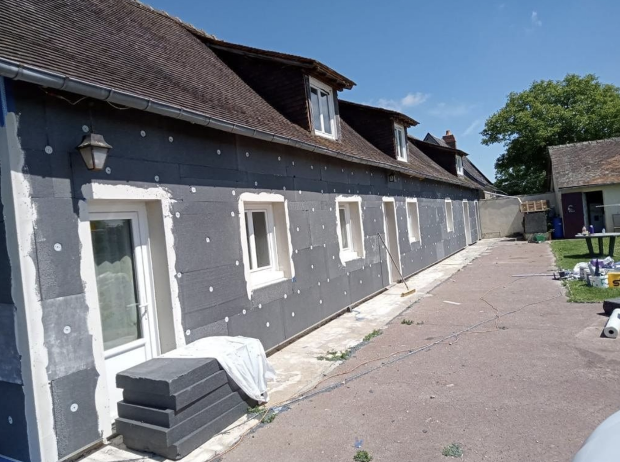 Longue façade en cours d’isolation par l’extérieur, isolant posé et chevillé