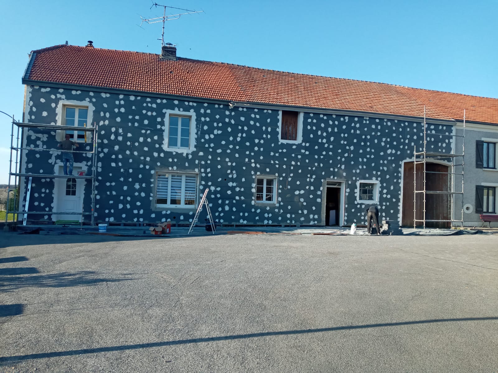 Longère recouverte de panneaux isolants chevillés, échafaudage en pignon