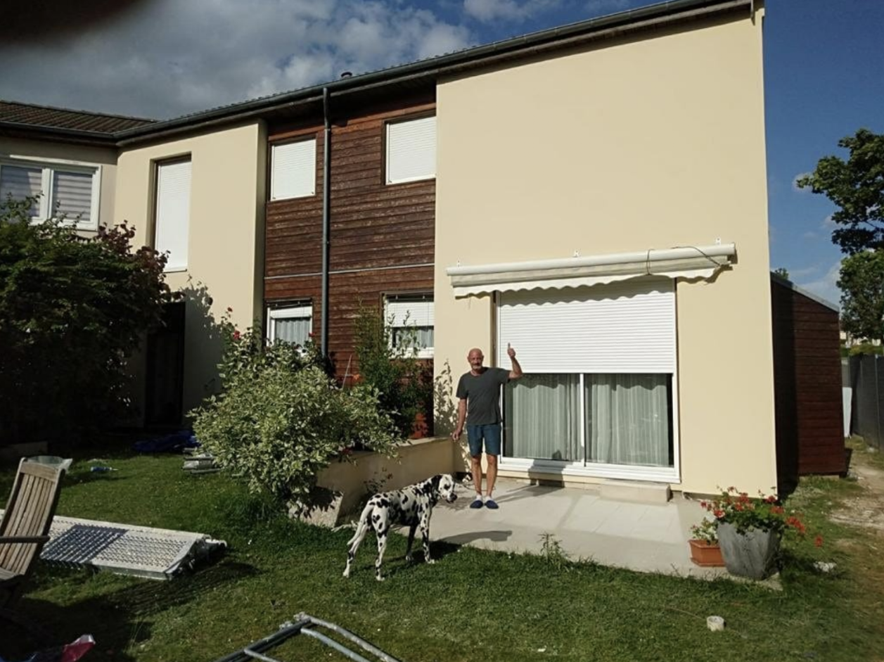 Propriétaire devant sa maison après isolation thermique extérieure, pouce levé