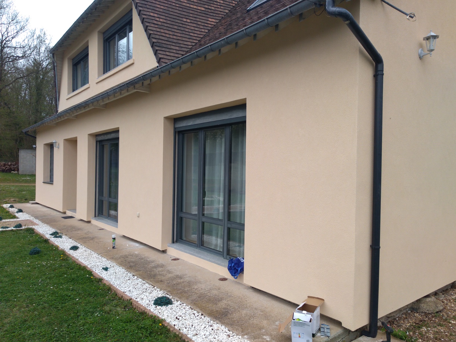 Maison à étage enduite en teinte claire avec baies vitrées